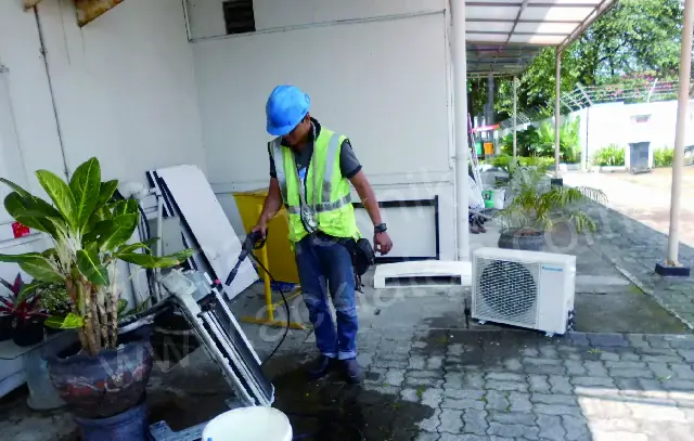 Cuci AC: teknisi membersihkan evaporator AC dengan semprotan air