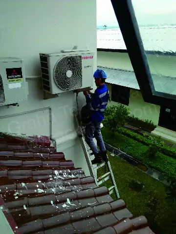 Pemasangan unit outdoor AC di dinding rumah menggunakan tangga